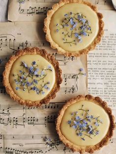 three small pies with flowers on top of sheet music paper next to each other