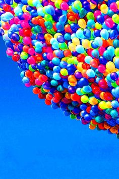 a bunch of balloons floating in the air with a blue sky behind them and a plane flying overhead