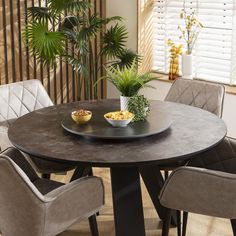 a round table with chairs around it in front of a plant and potted palm tree