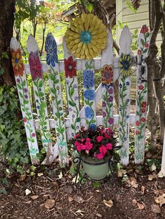 a potted plant sitting in front of a wooden fence with flowers painted on it