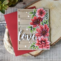 a card with flowers and the word love on it, sitting next to a piece of wood