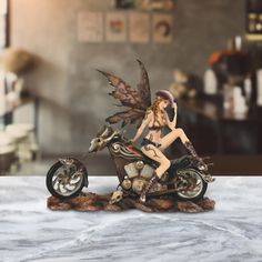 a statue of a fairy sitting on a motorcycle