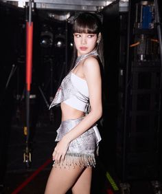 a woman in a silver and white outfit posing for the camera with her hands on her hips