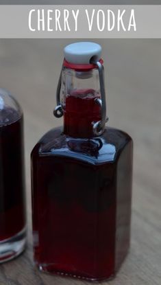 a bottle of cherry vodka sitting on top of a wooden table next to another bottle