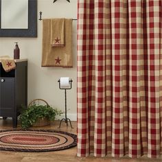 a red and white checkered shower curtain next to a rug on the floor in front of a mirror