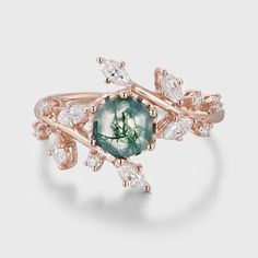 a rose gold ring with green and white stones in the center, surrounded by diamonds