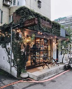 a store front with plants growing on the side of it's windows and doors