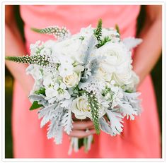 a bridesmaid holding a bouquet of white flowers and greenery in her hands