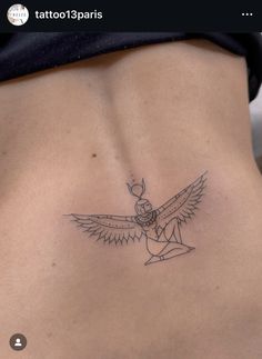 the back of a woman's stomach with an egyptian winged tattoo on her left side