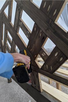 a person using a power drill to fix a wooden structure