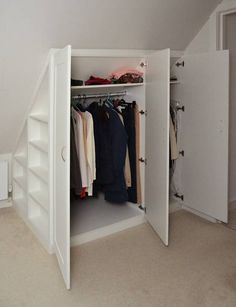 an open closet with clothes on hangers and other items in the space underneath it