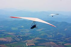 two hang gliders in the air over farmland