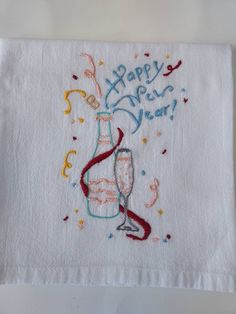 a happy new year embroidered on a white napkin with confetti and wine glasses