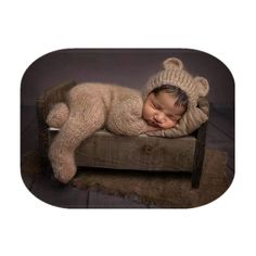 a baby sleeping on top of a wooden chair wearing a knitted hat and sweater