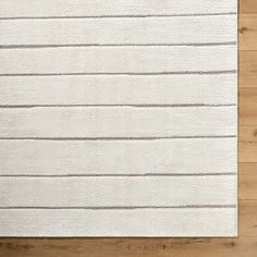 a white rug with vertical lines on it in the middle of a wood flooring area