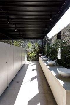 a row of white sinks sitting next to each other on top of a cement floor