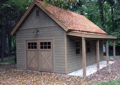 a small garage with a red roof in the middle of some leaves on the ground