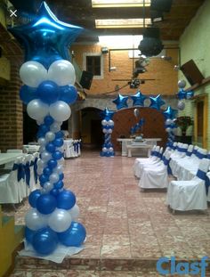 blue and white balloons are hanging from the ceiling in an indoor event hall with tables set up for people to sit at