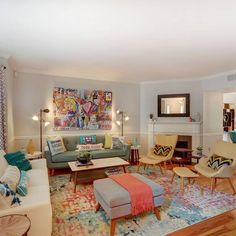 a living room filled with furniture and a painting on the wall above it's fireplace