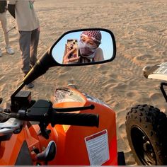 a person is taking a photo in the side mirror of a motorcycle on the beach