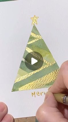 someone is drawing a christmas tree on paper with gold foil and a green marker in front of it