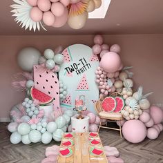 a table topped with watermelon slices next to balloons and other items in front of a wall