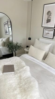 a white bed sitting in a bedroom next to a table with a mirror on it