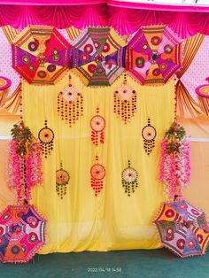 an elaborately decorated stage with umbrellas and flowers on the side, in front of pink drapes