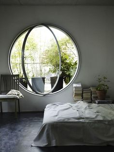 a bed sitting under a round window in a bedroom