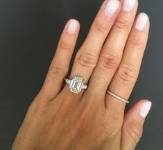 a woman's hand holding an engagement ring with a diamond in the middle and a band around it