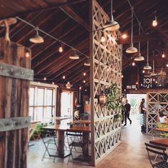 the inside of a restaurant with tables, chairs and lights hanging from the rafters