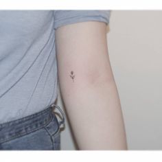 a woman's arm with a small flower tattoo on the left side of her arm