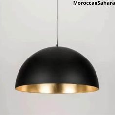 a black and gold pendant light hanging from a white wall with the words moroccan sahara on it