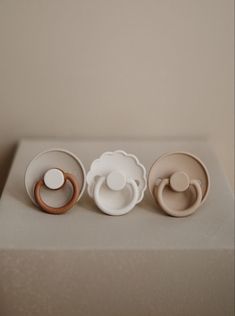 three baby cups and one pacifier sit on a table