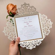 a person holding up a wedding card with a rose on it and the letter ajj