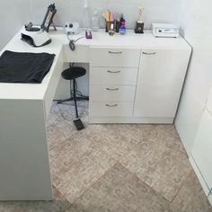 a white desk topped with lots of clutter next to a wall mounted microwave oven