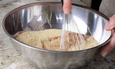 a person mixing food in a metal bowl