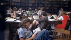 people sitting at desks in a library reading books