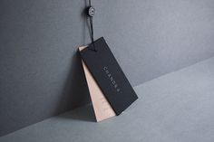 a black tag hanging from the side of a gray wall with a string attached to it