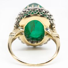 The Melinda ring is an authentic vintage design. This ring centers one natural cabochon cut emerald that weighs 18ctw approx. and is surrounded by 22 old mine cut diamonds of I color, VS2 clarity that weigh 1.30ctw. The stones are set in a platinum setting with details in 18k gold. Vintage Green Emerald Ring With Rose Cut Diamonds, Vintage Oval Emerald Ring With Rose Cut Diamonds, Antique Green Oval Diamond Ring, Antique Emerald Ring Oval Cabochon, Antique Emerald Ring With Oval Cabochon, Antique Cabochon Emerald Wedding Ring, Vintage Cabochon Emerald Ring For Anniversary, Antique Diamond Cabochon Rings, Vintage Diamond Cabochon Rings