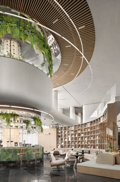 the lobby is very large and has plants growing on the ceiling, along with modern furniture