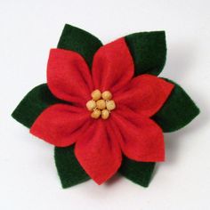 a red poinsettia with green leaves and gold centers on a white surface