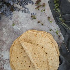 three tortillas sitting on top of a piece of cloth next to some flowers