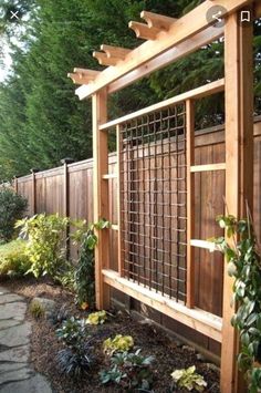 a garden area with a wooden fence and stone path leading to the side of the yard