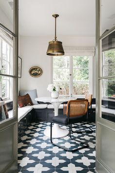 a dining room with black and white tile flooring next to a large open window