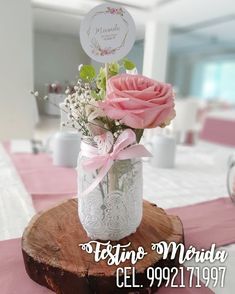 pink roses in a mason jar with baby's breath on a wood slice at a wedding reception