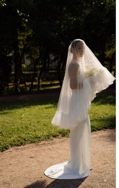 a woman wearing a veil and holding a bouquet in her hand is standing on the ground