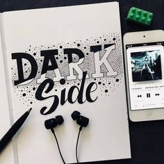 an iphone and headphones sitting next to a notebook with the words dark side on it