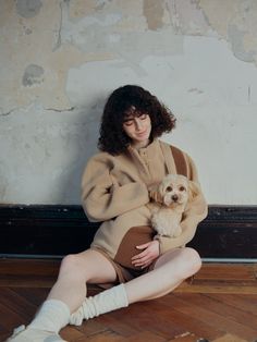 a woman sitting on the floor holding a dog