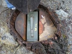 a piece of metal sitting on top of a tree stump next to a person's foot